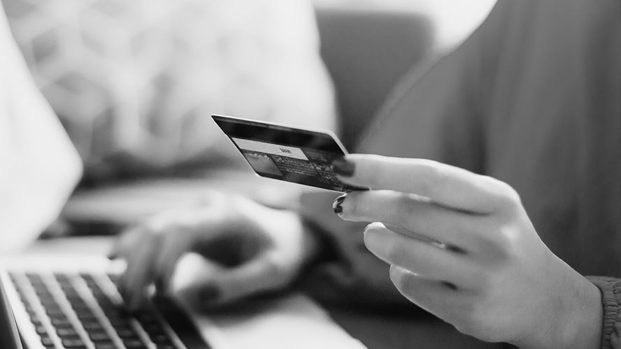 Person holding a credit card while working on a laptop.